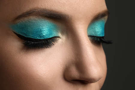 Young woman with evening makeup on gray background, closeup. Eye shadow product