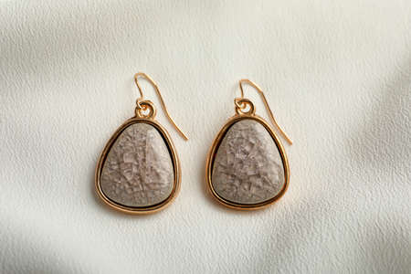 Elegant earrings on white fabric, flat lay. Stylish bijouterie