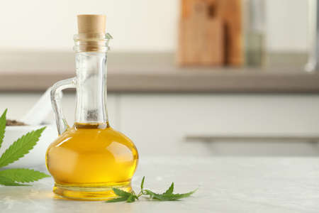 Hemp oil and leaves on light table against blurred background. Space for textの写真素材