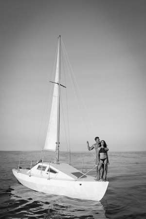 Young man and his beautiful girlfriend in bikini on yacht. Black and white toneの写真素材