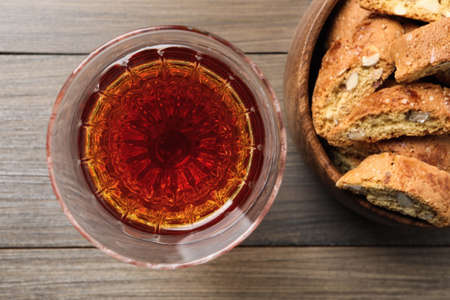 Tasty cantucci and glass of liqueur on wooden table, flat lay. Traditional Italian almond biscuits