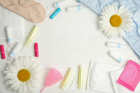 Frame of tampons and other menstrual hygienic products on white wooden background, flat lay. Space...