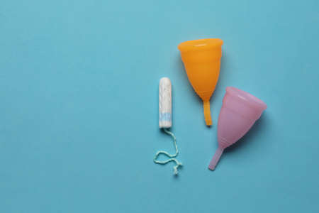Menstrual cups near tampon on light blue background, flat lay with space for text. Reusable and disposable feminine productsの写真素材