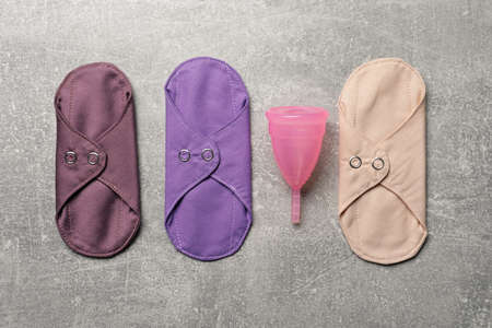 Menstrual cup and cloth pads on gray background, flat lay. Reusable feminine hygiene productsの写真素材