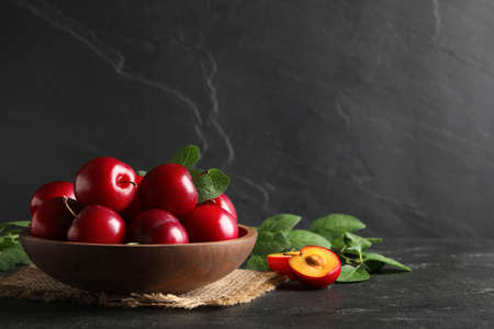 Delicious ripe cherry plums with leaves on black table. Space for textの写真素材
