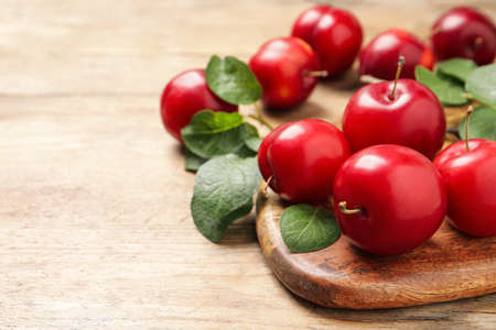 Delicious ripe cherry plums with leaves on wooden table, closeup. Space for textの写真素材