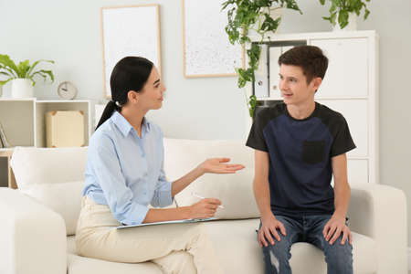 Young psychologist working with teenage boy in officeの写真素材