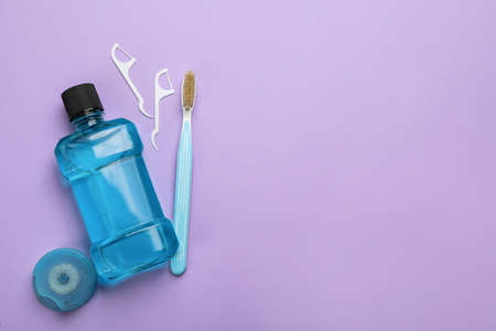 Mouthwash, toothbrush and dental floss on violet background, flat lay. Space for textの写真素材