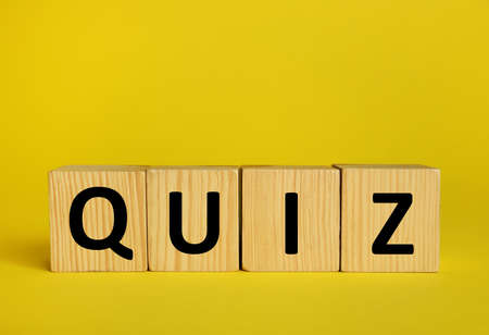 Wooden cubes with word Quiz on yellow background. Space for text