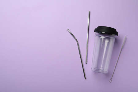 Glass cup, metal straws and brush on violet background, flat lay with space for text. Conscious consumptionの写真素材