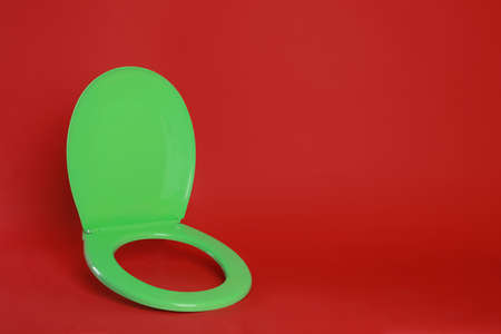 New green plastic toilet seat on red background, space for textの写真素材