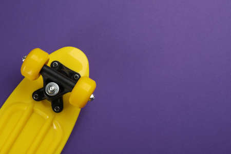 Skateboard on purple background, top view. Space for text