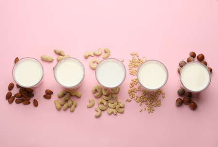Different vegan milks and nuts on pink background, flat layの写真素材