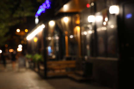 Blurred view of modern cafe with outdoor terrace at night