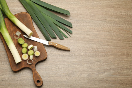 Fresh raw leeks and knife on wooden table, flat lay. Space for textの写真素材