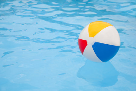 Inflatable colorful beach ball floating on water in swimming pool, space for textの写真素材
