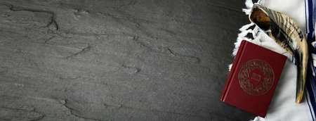 Tallit, shofar and book Torah with text in Hebrew on black table, flat lay with space for text. Rosh hashanah celebrationの写真素材