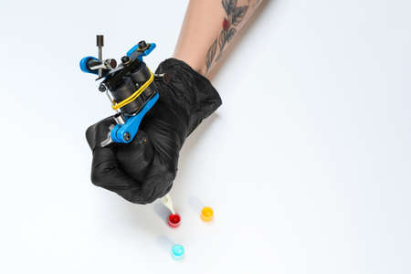 Tattoo artist with professional machine and colorful ink on white background, closeupの写真素材