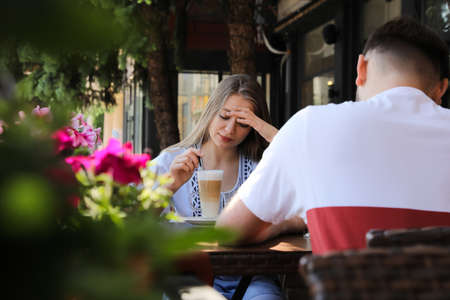 Young woman having boring date with guy in outdoor cafeの写真素材