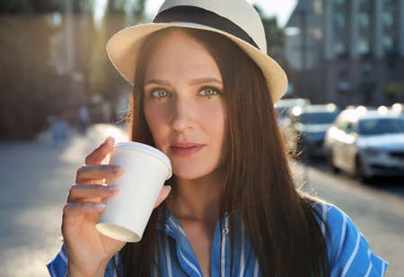 Beautiful young woman with nose piercing drinking coffee outdoorsの写真素材