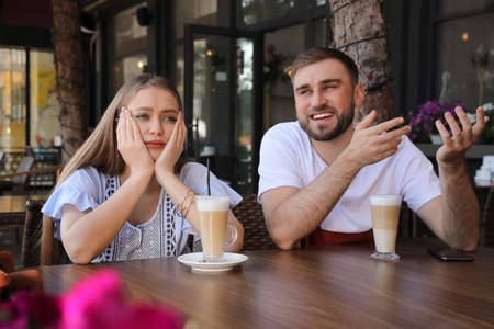 Young woman having boring date with talkative guy in outdoor cafeの写真素材