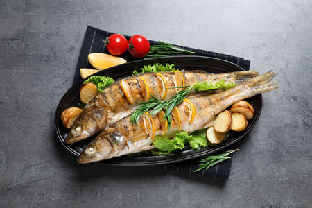 Tasty homemade roasted pike perches served on gray table, top view. River fish
