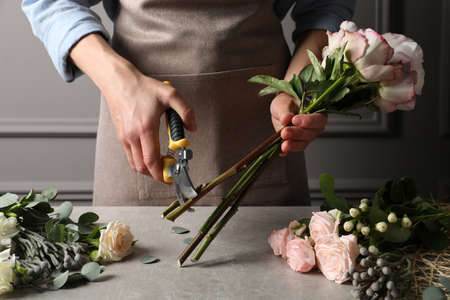 Florist cutting flower stems with pruner at workplace, closeup