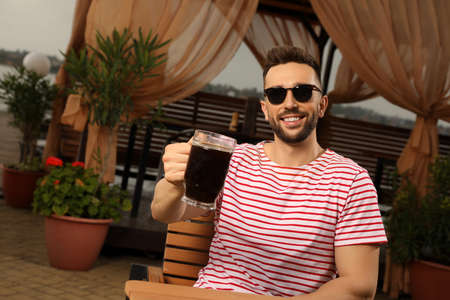 Man with glass of dark beer in outdoor cafe, space for text