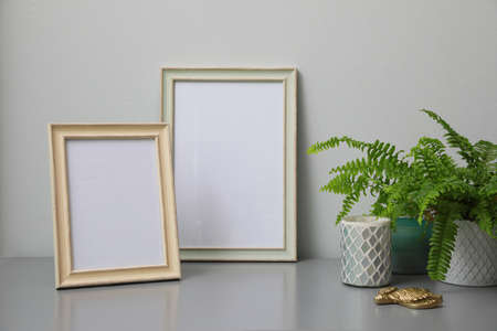 Empty photo frames, candles and green plant on gray tableの写真素材