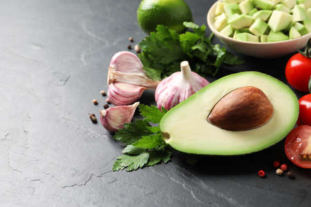 Fresh guacamole ingredients on black table. Space for text