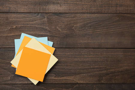 Stack of colorful stickers on wooden table, top view. Space for text