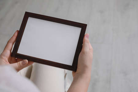 Woman holding empty photo frame indoors, closeupの写真素材