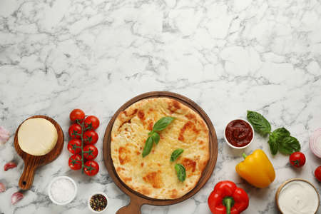 Delicious khachapuri with cheese surrounded by different products on white marble table, flat lay. Space for textの写真素材