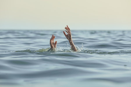 Drowning woman reaching for help in seaの写真素材