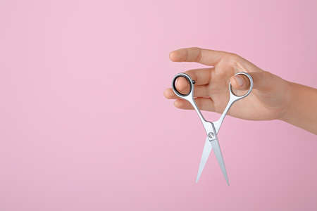 Hairdresser holding professional scissors and space for text on pink background, closeup. Haircut toolの写真素材