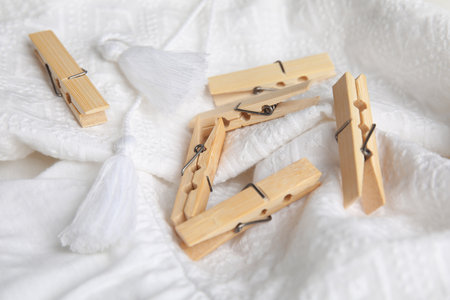 Many wooden clothespins on white garment, closeup viewの写真素材