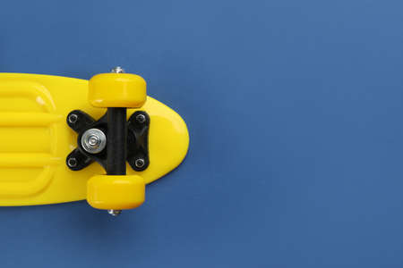 Yellow skateboard on blue background, top view. Space for textの写真素材