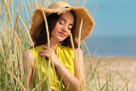 Beautiful young woman wearing straw hat on beach. Stylish headdress