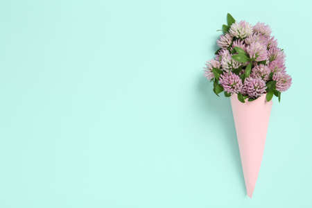 Bouquet of beautiful clover flowers on turquoise background, top view. Space for textの写真素材