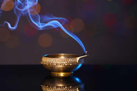 Blown out diya on dark background with blurred lights. Diwali lamp
