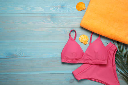 Beach towel and swimsuit on light blue wooden background, flat lay. Space for textの写真素材