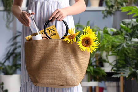 Woman putting bottle of water in beach bag indoors, closeupの写真素材