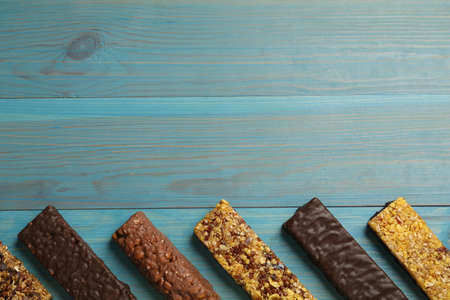 Different tasty protein bars on light blue wooden table, flat lay. Space for textの写真素材