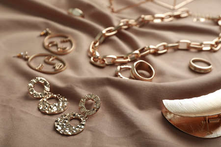 Stylish golden bijouterie on light brown fabric, closeupの写真素材