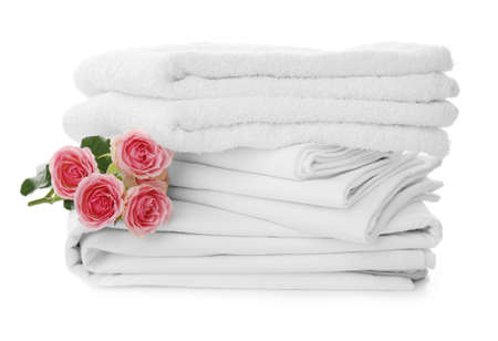 Stack of towels and bed sheets with roses on white backgroundの写真素材