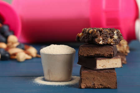Different energy bars and protein powder on blue wooden table, closeupの写真素材
