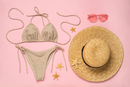 Stylish bikini, straw hat, sunglasses and starfishes on pink background, flat layの写真素材