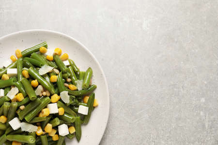 Delicious salad with green beans, corn and cheese on light table, top view. Space for textの写真素材