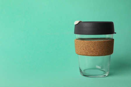 Glass cup with sleeve on turquoise background, space for text. Conscious consumption