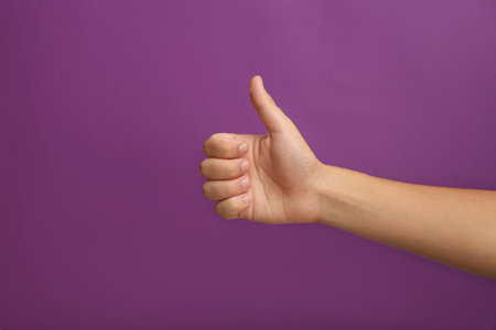 Teenage boy showing thumb up on purple background, closeupの写真素材